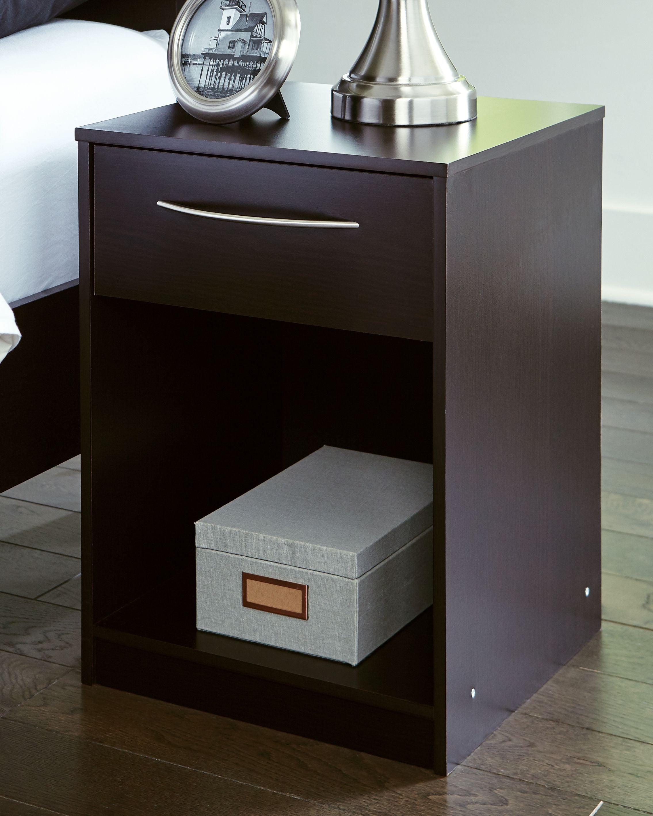 Dark wood one-drawer night stand with open shelf holding a light gray storage bin