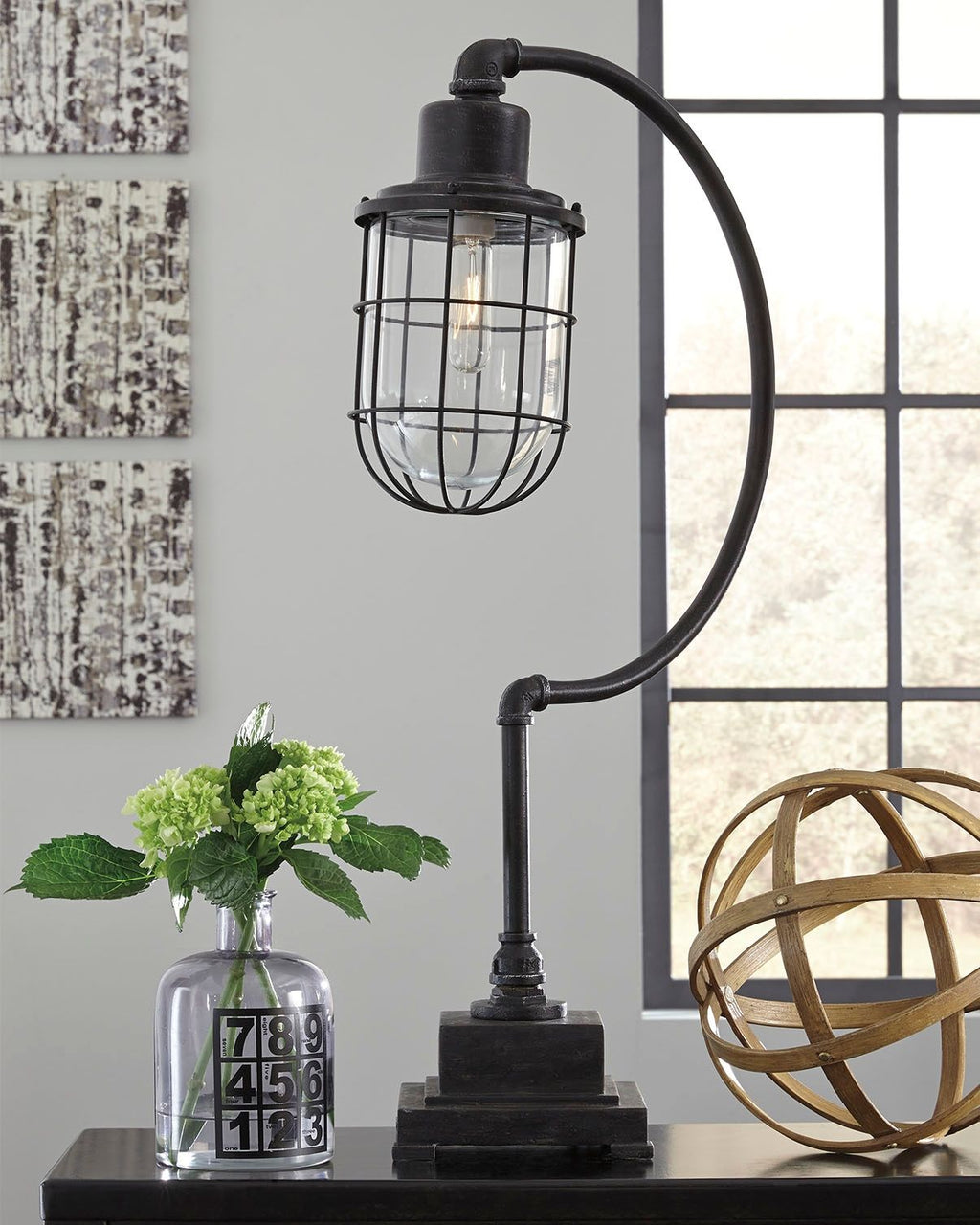 Antique black metal desk lamp with round glass cage shade and exposed bulb