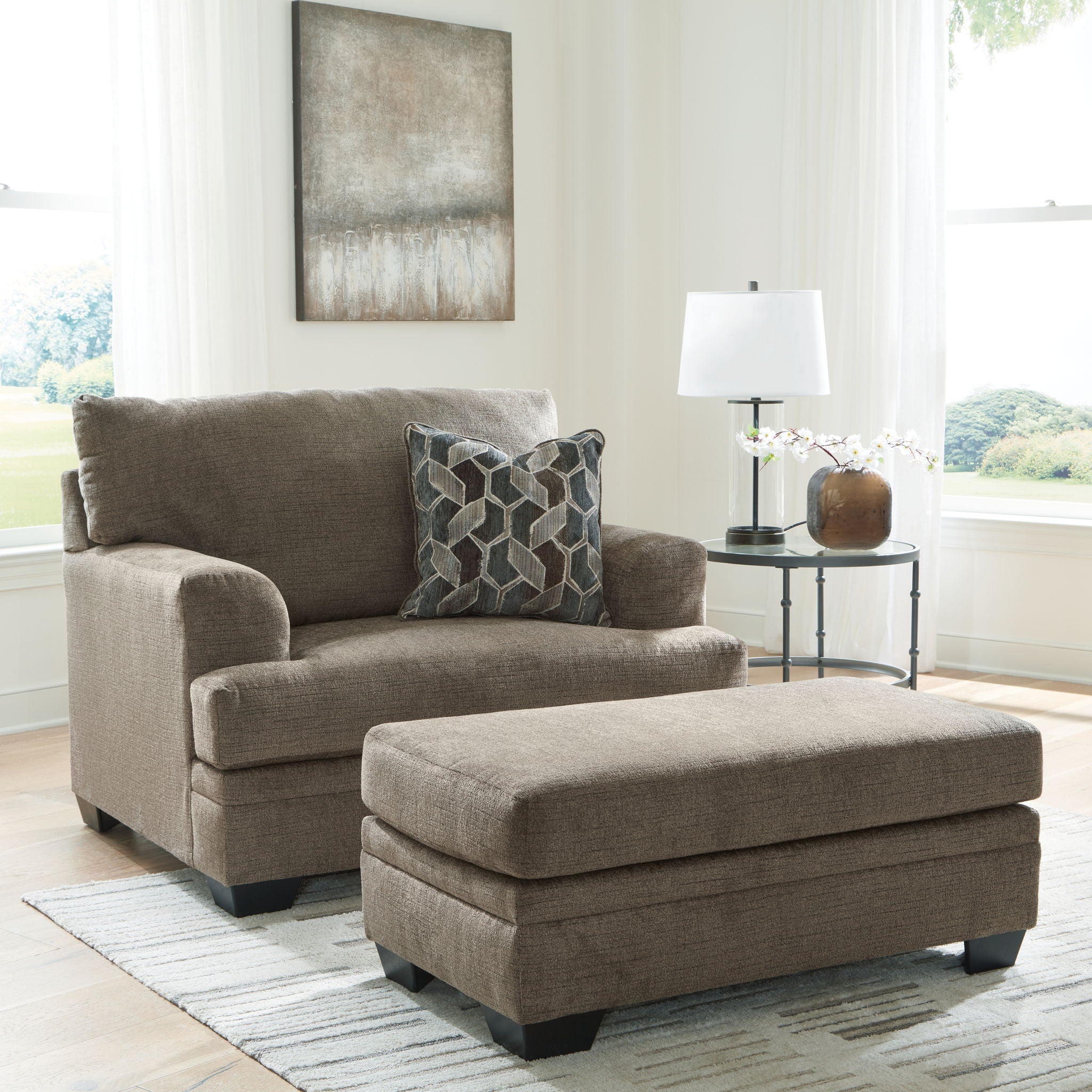 Taupe fabric loveseat with matching ottoman and geometric patterned throw pillows
