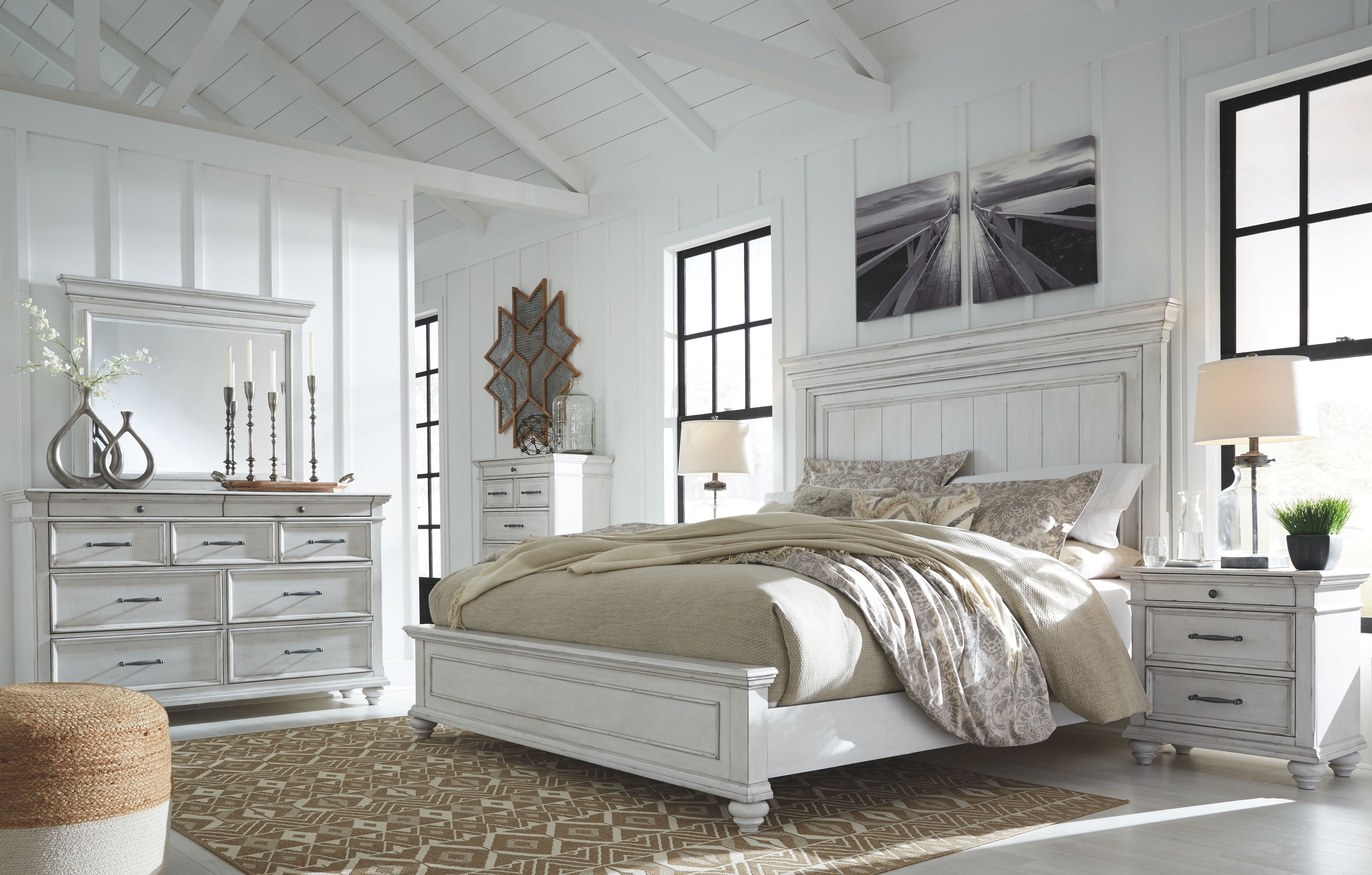 White panel bed with beige bedding, two nightstands, and panel wall headboard detail