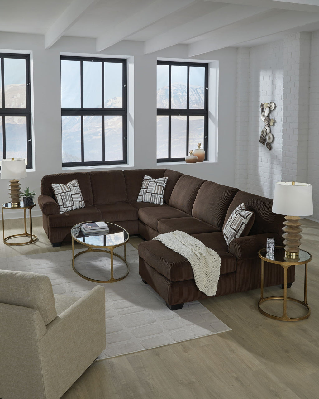 Chocolate sectional sofa with chaise seating, patterned pillows, and a throw blanket