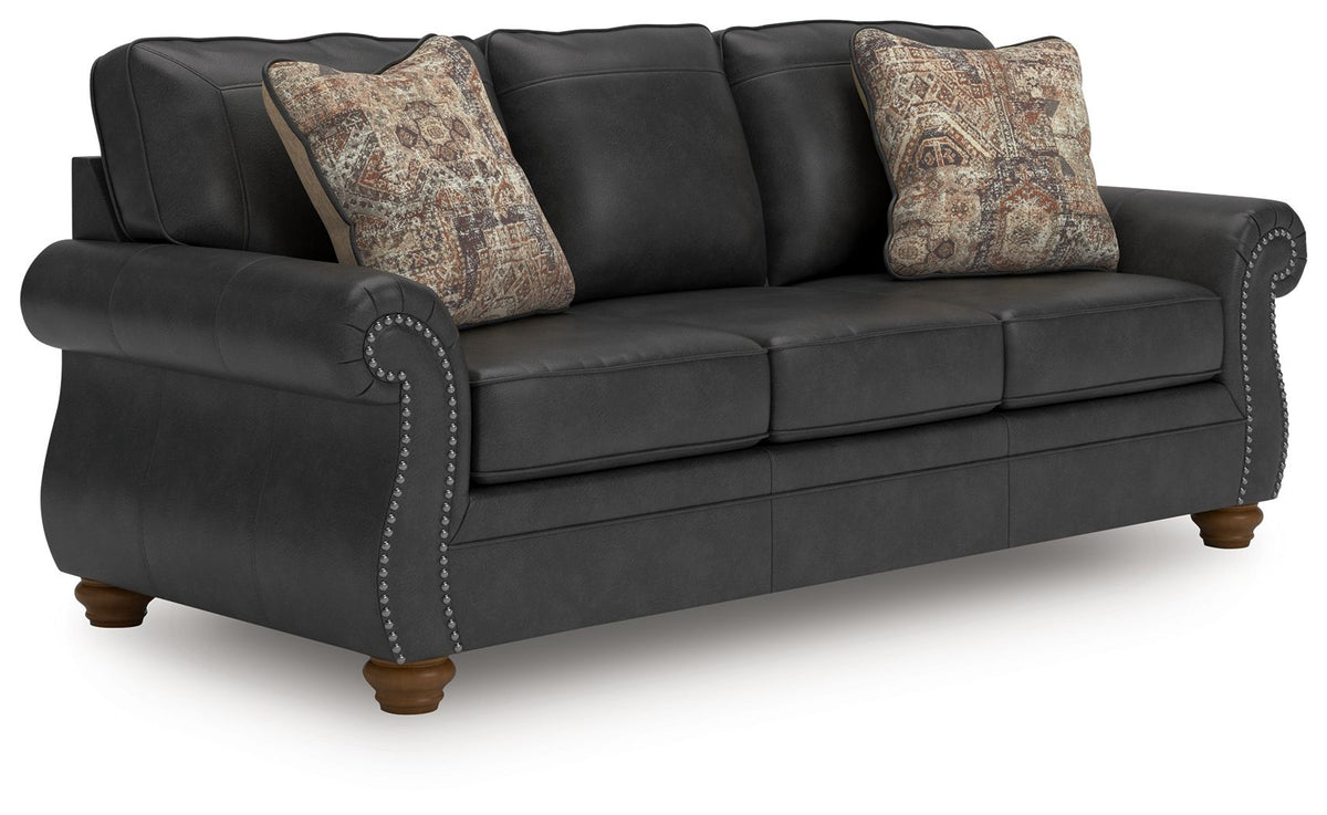 Dark gray sofa with tufted arm trim and two patterned throw pillows