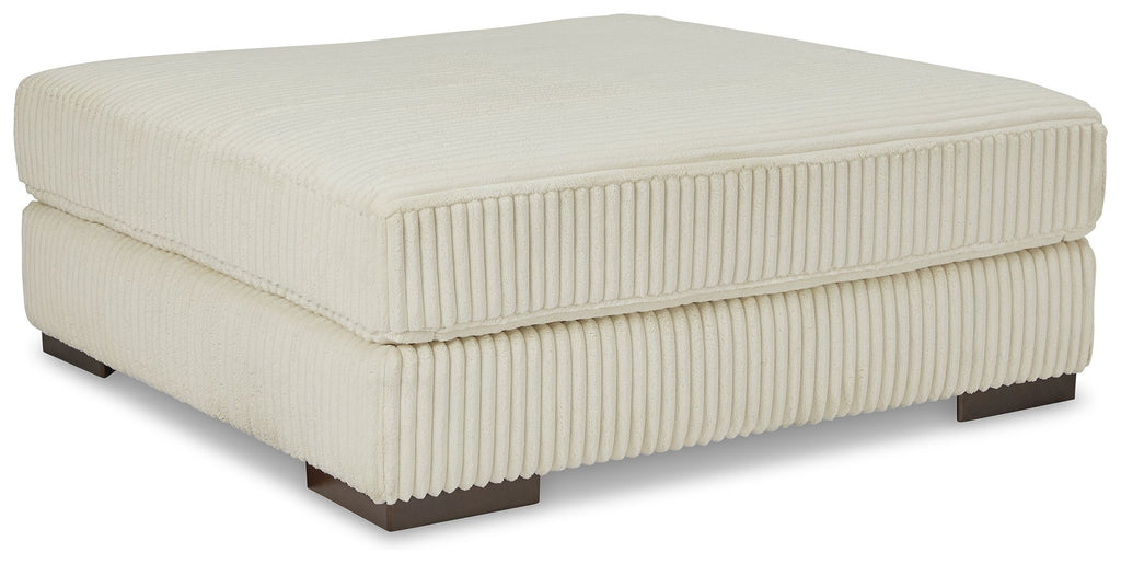 Beige oversized ottoman with ribbed fabric cover and square padded top on dark legs