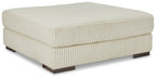 Beige oversized ottoman with ribbed fabric cover and square padded top on dark legs