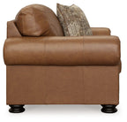 Brown upholstered armchair with curved back, rolled arms, and patterned throw pillow