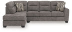 Dark gray 2-piece sectional sofa with left chaise, tufted back, and two striped throw pillows