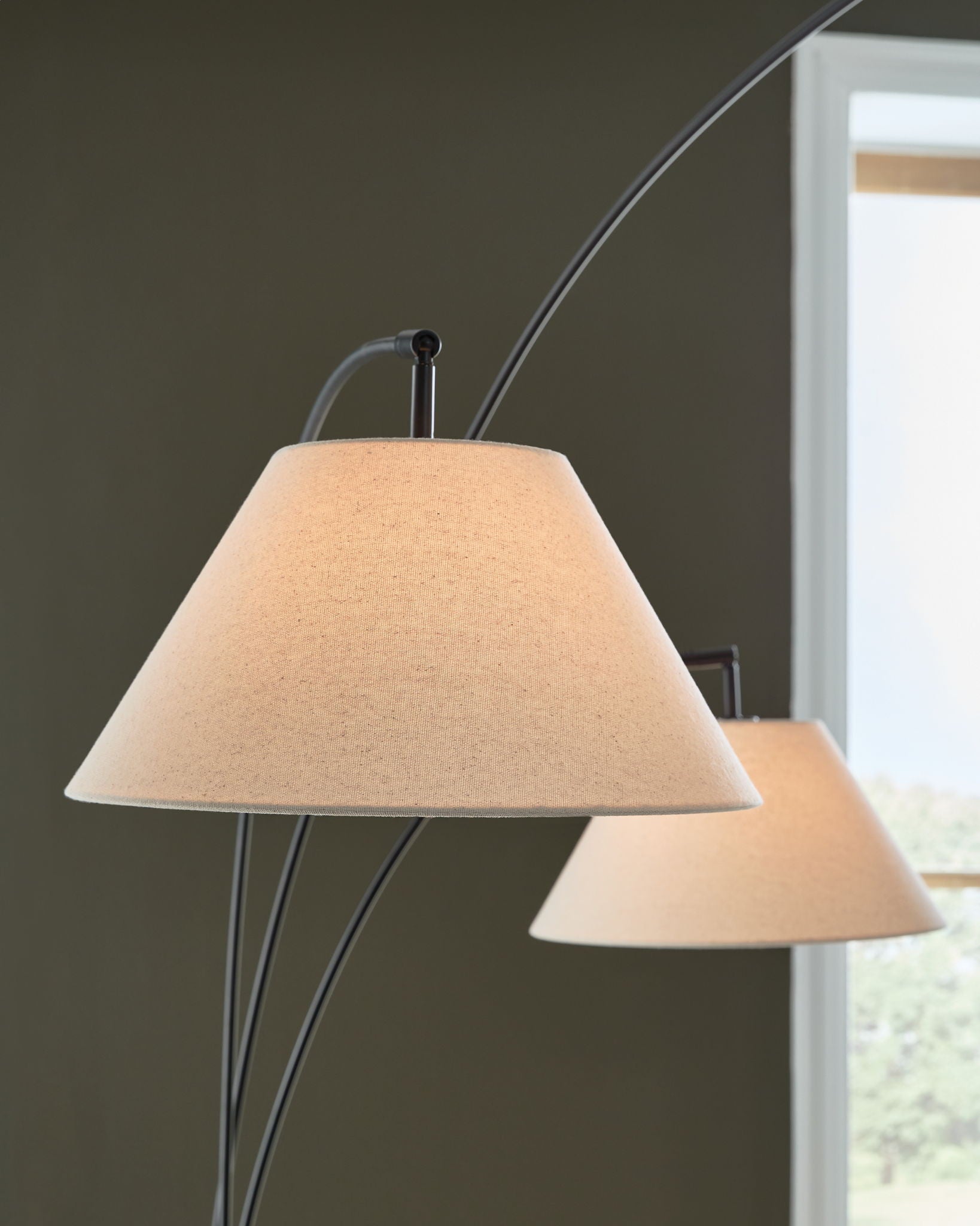 Arc floor lamp with three white fabric shades on black metal curved arms