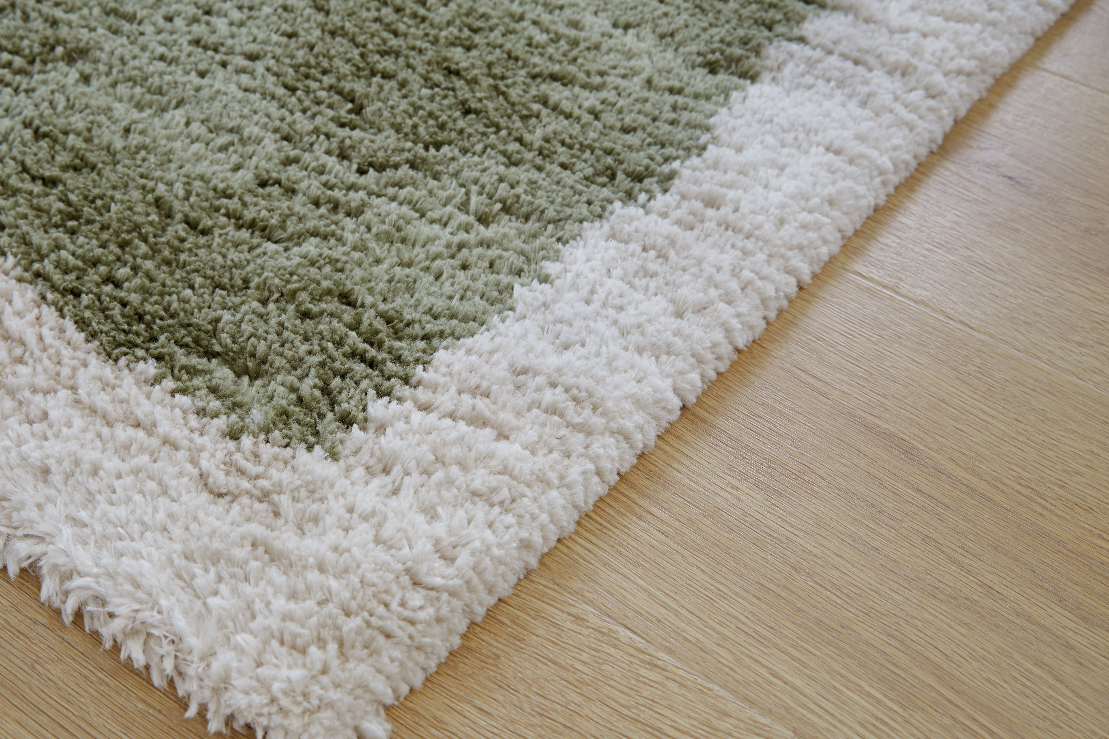 Textured green-and-beige shag rug edge with fringes, dense looped pile