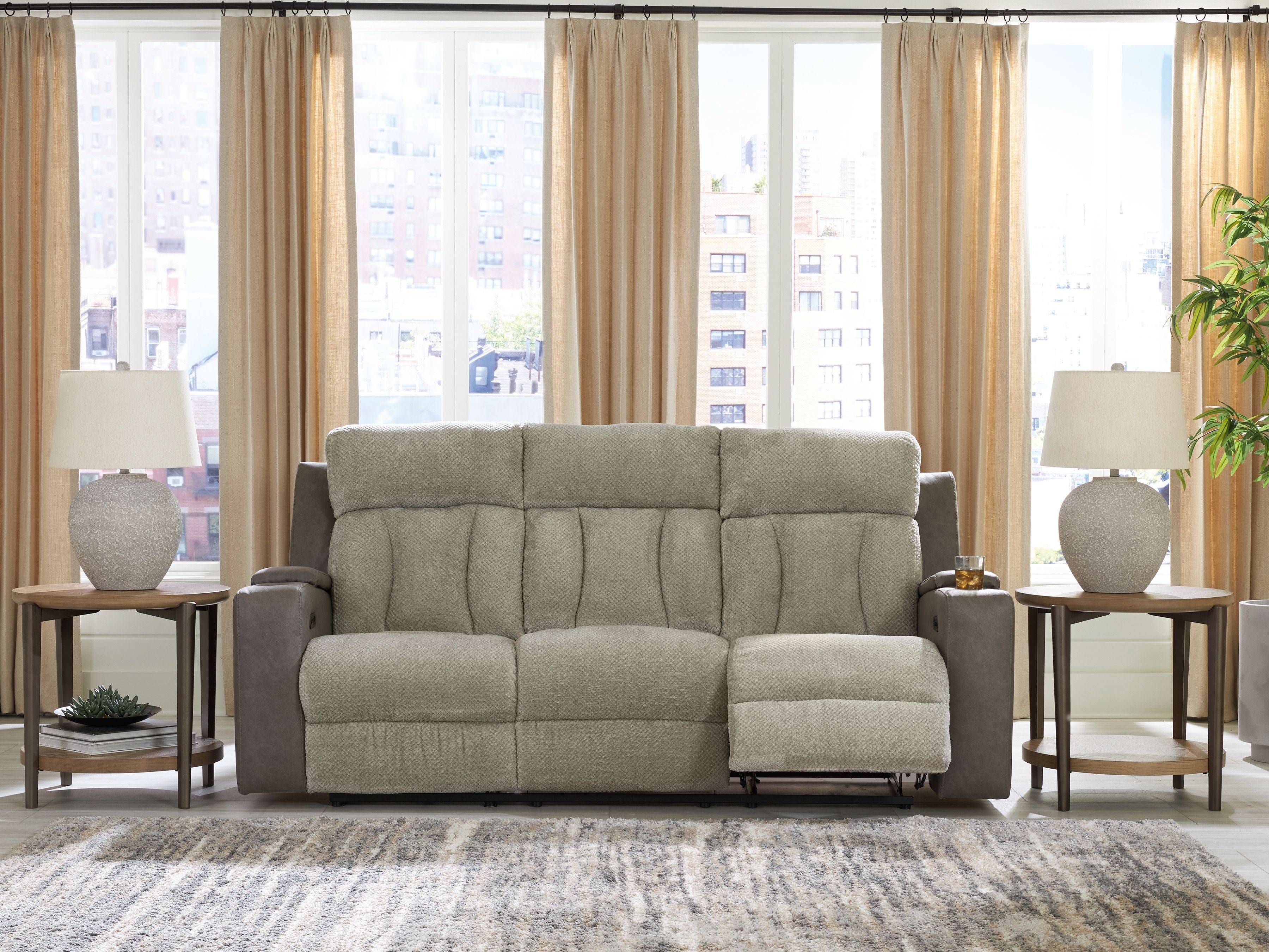 Power reclining sofa in light tan upholstery with padded arms and matching ottoman