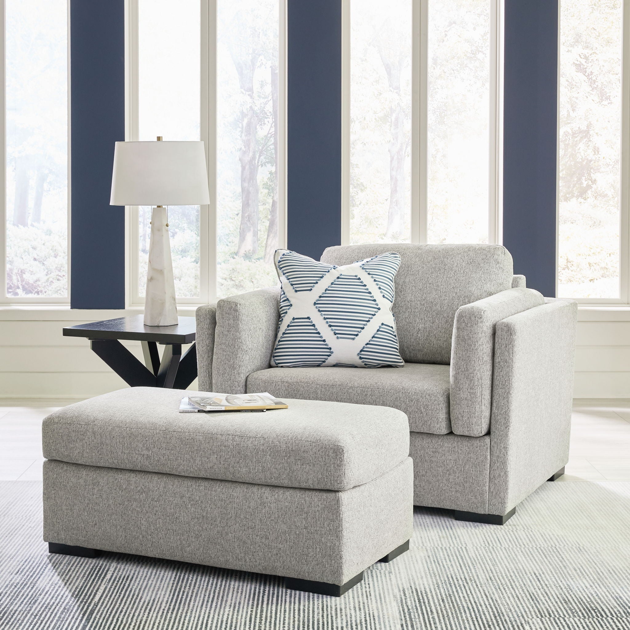 Light gray living room chair and ottoman set with patterned throw pillow and side table
