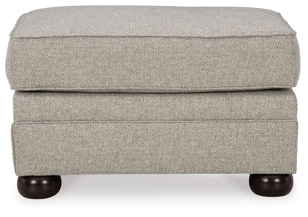 Light beige ottoman with padded hinged lid and dark rounded wooden feet