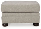 Light beige ottoman with padded hinged lid and dark rounded wooden feet