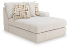 Light beige corner chaise with two patterned throw pillows and rounded arms