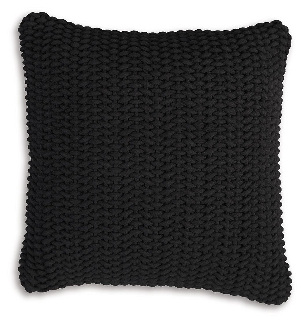 Black knitted square pillow with dense braided texture and scalloped border edge.