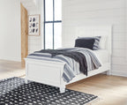 White panel bed with upholstered frame, showing black-and-white striped bedding.