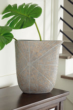 Blue-gray vase with radial mosaic pattern holding green leaves