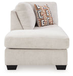 Stone corner chaise seat with rounded arm and patterned throw pillow