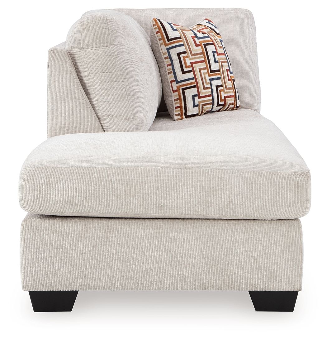 Stone corner chaise seat with rounded arm and patterned throw pillow