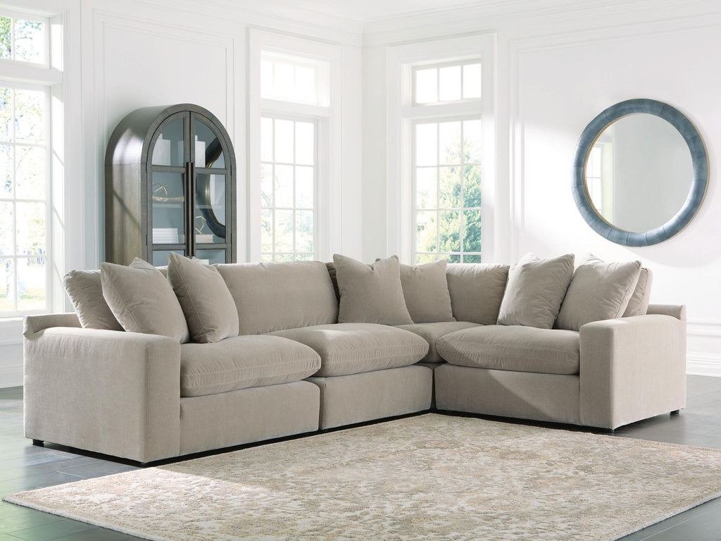 Light gray sectional sofa with deep seats, square arms, and stacked back cushions along the back.