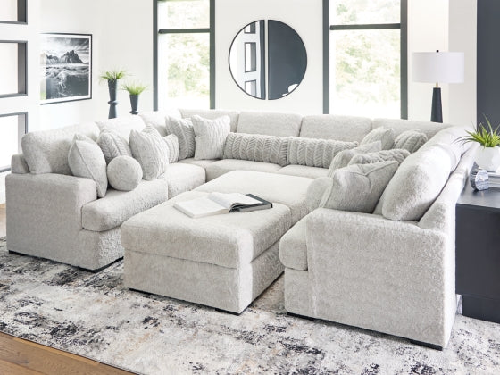 Light gray sectional sofa with chaise and ottoman, tufted back and wide cushions