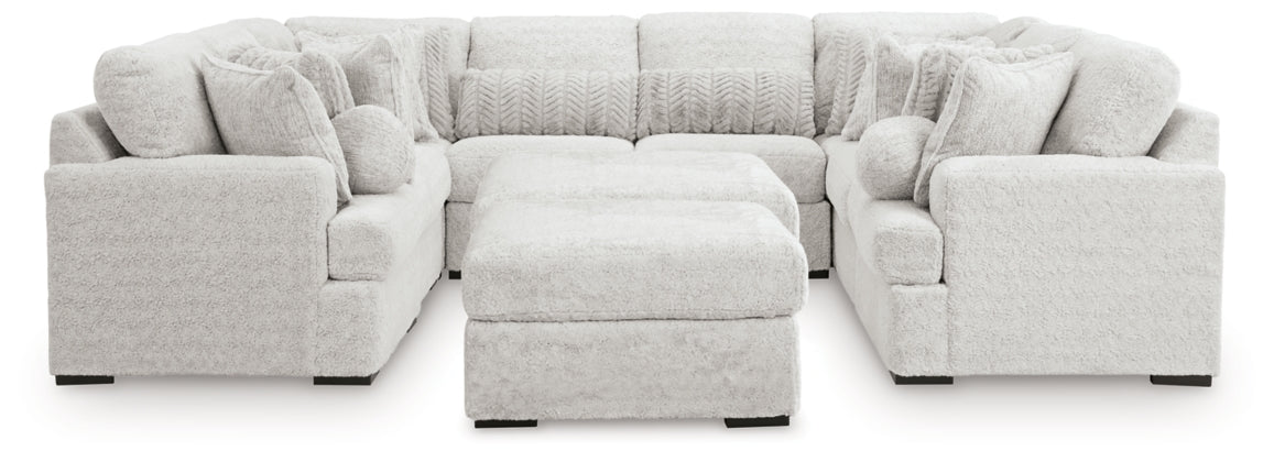 Light gray sectional sofa with ottoman and rounded armrests, armless chaise section
