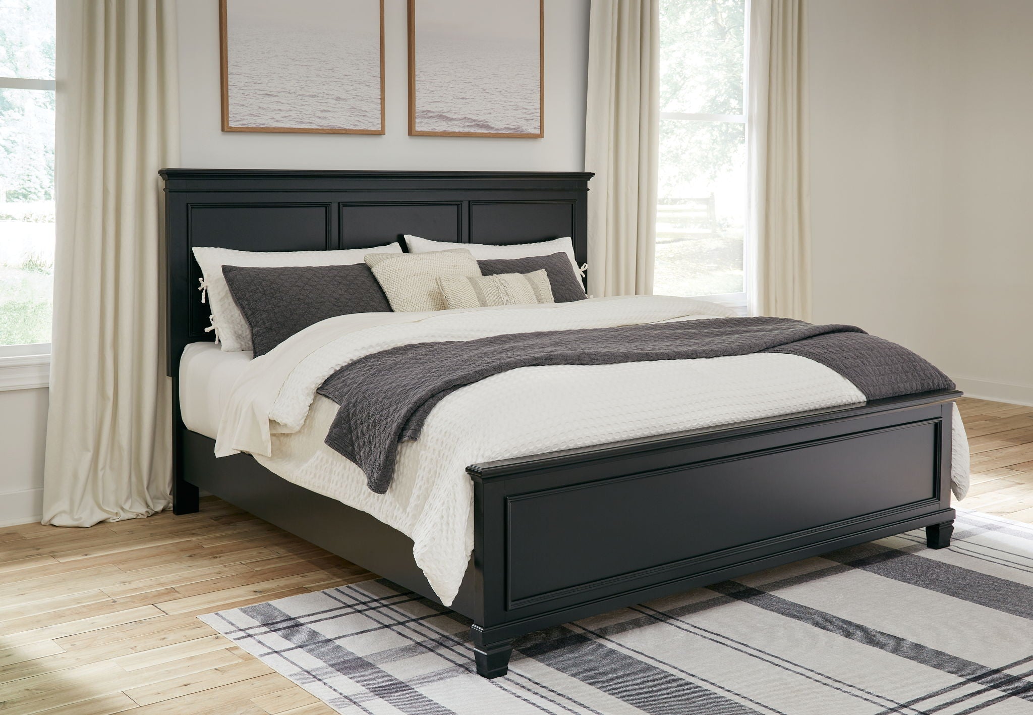 Black panel bed with one storage drawer beneath the frame and styled bedding.