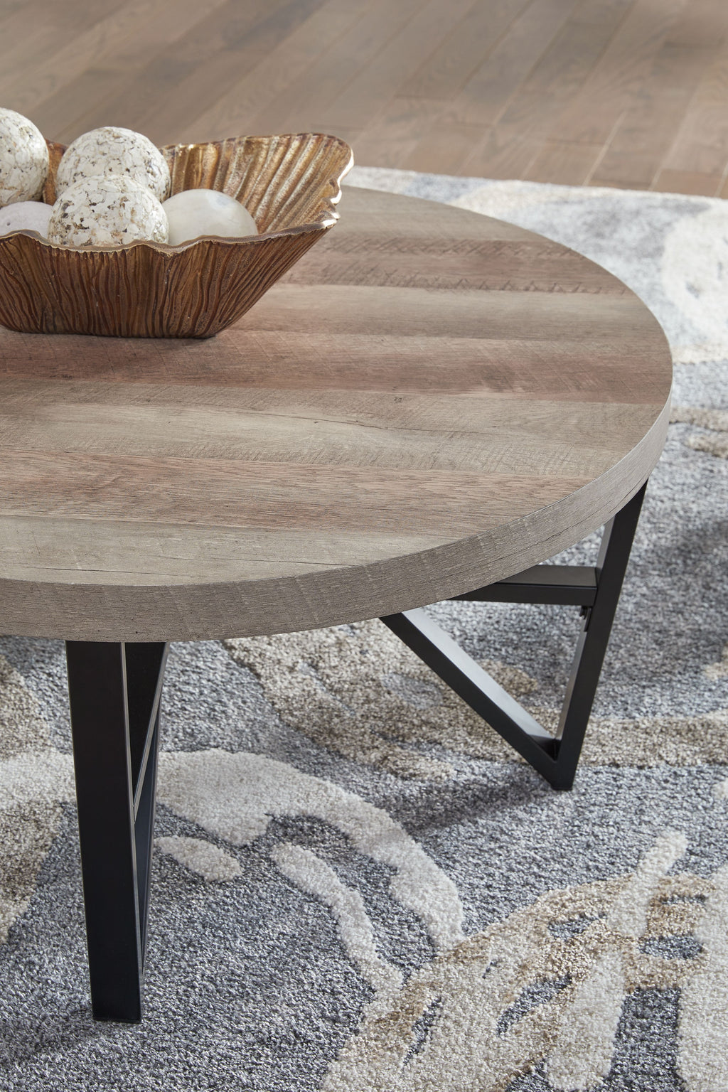 Round table top with grayish-brown wood grain and black cross-brace legs