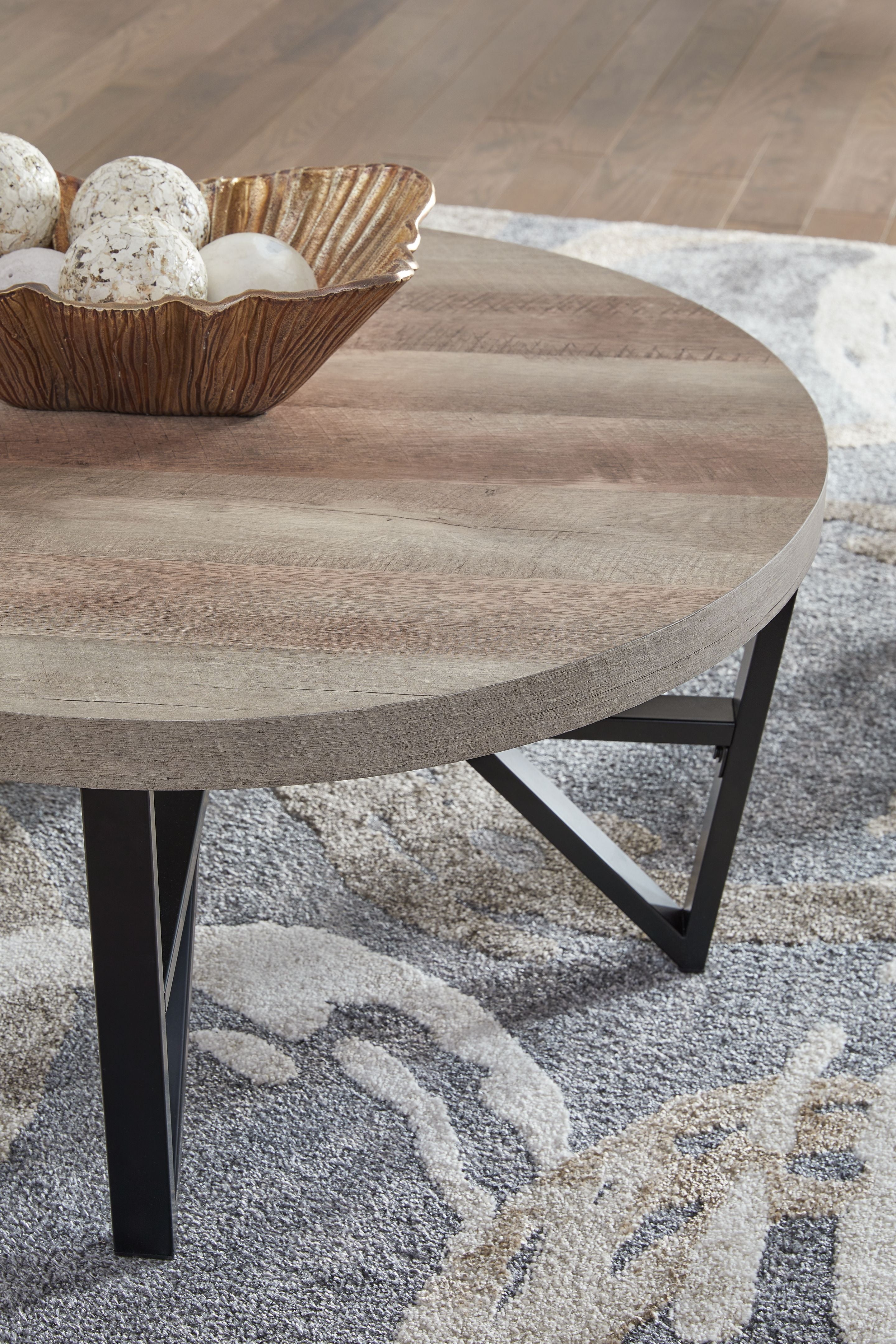 Round table top with grayish-brown wood grain and black cross-brace legs