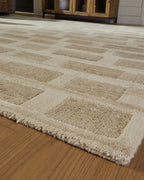 Beige geometric rug with textured edges, angled view on hardwood floor