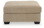 Light beige oversized ottoman with ribbed fabric, square padded top, dark legs.
