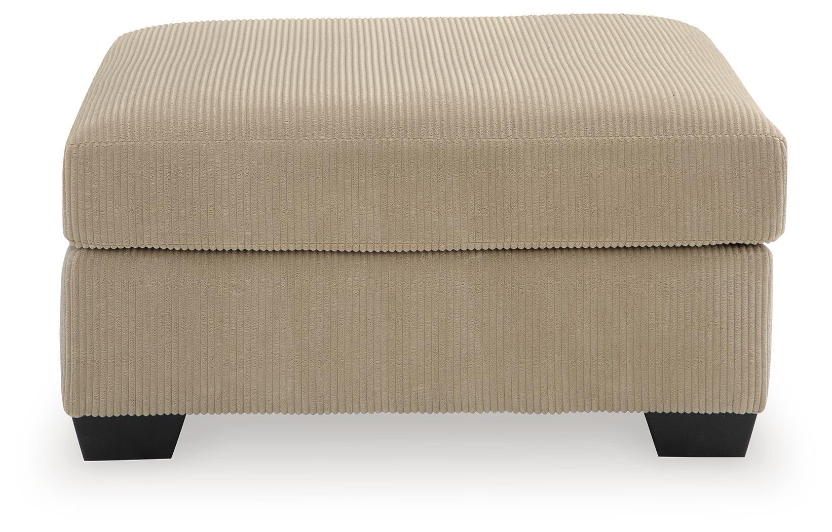 Light beige oversized ottoman with ribbed fabric, square padded top, dark legs.