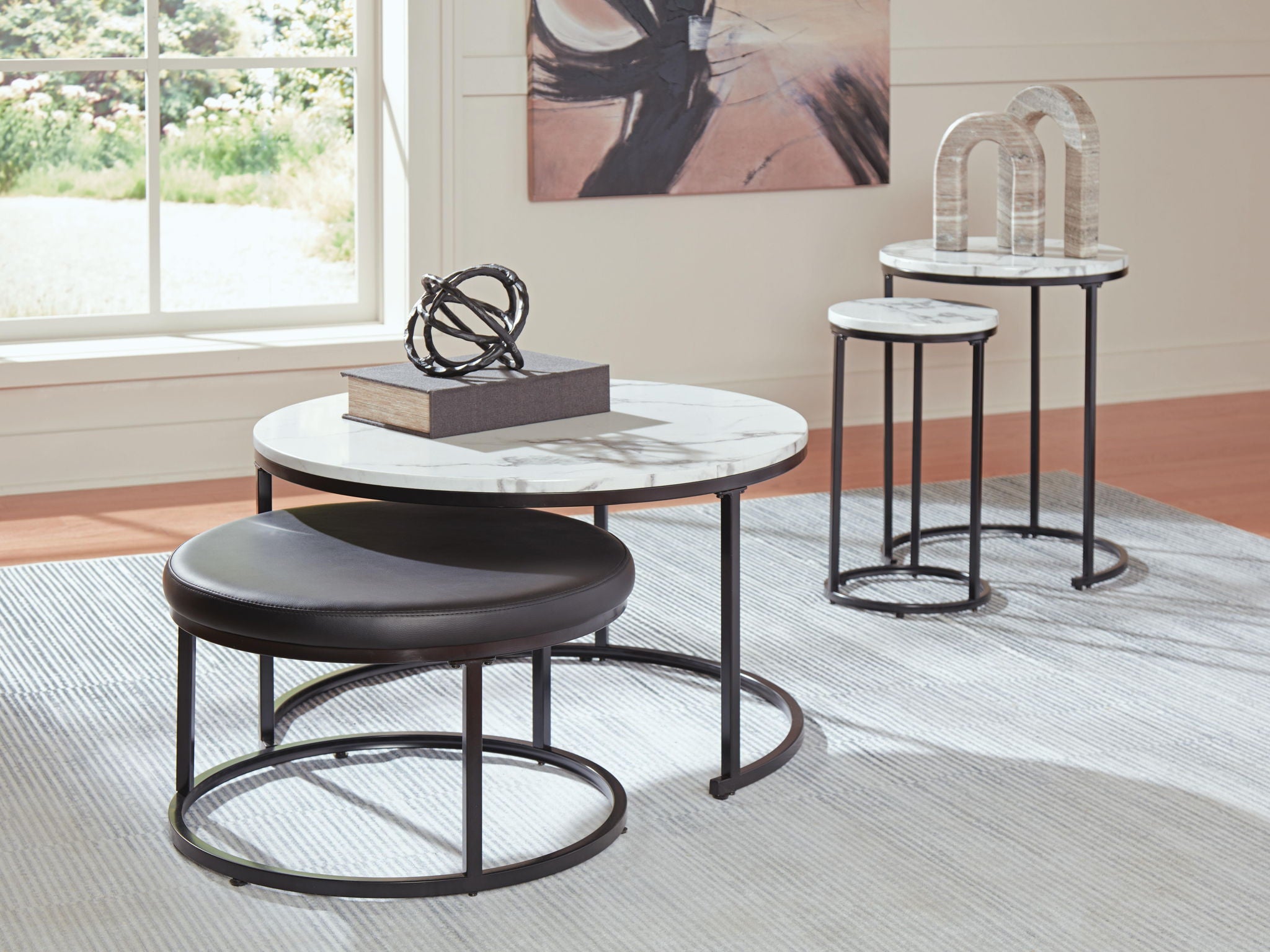 Set of black nesting tables with round white marble-look tops and dark cushioned seat