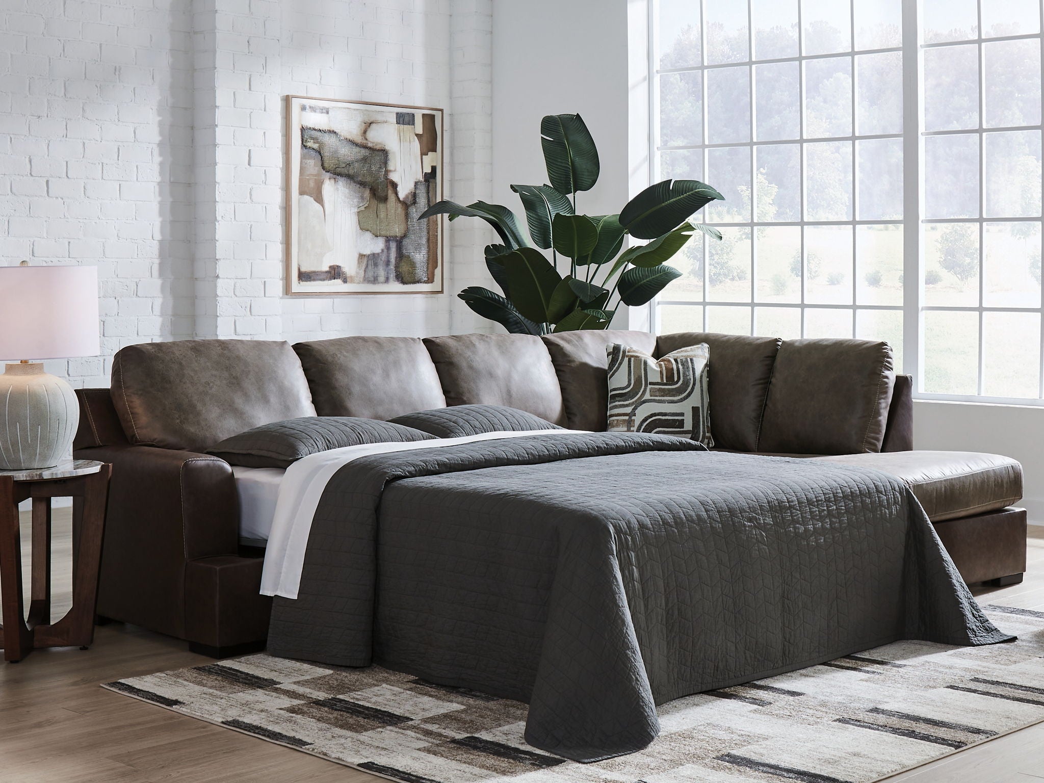 Dark fossil sectional sofa with chaise, gray pillows, and a draped throw blanket