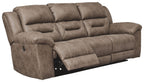 Taupe-gray power reclining sofa with reclining chaise footrest and padded arms.