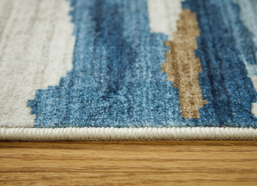 Blue abstract rug pile close-up with beige accents and braided edge