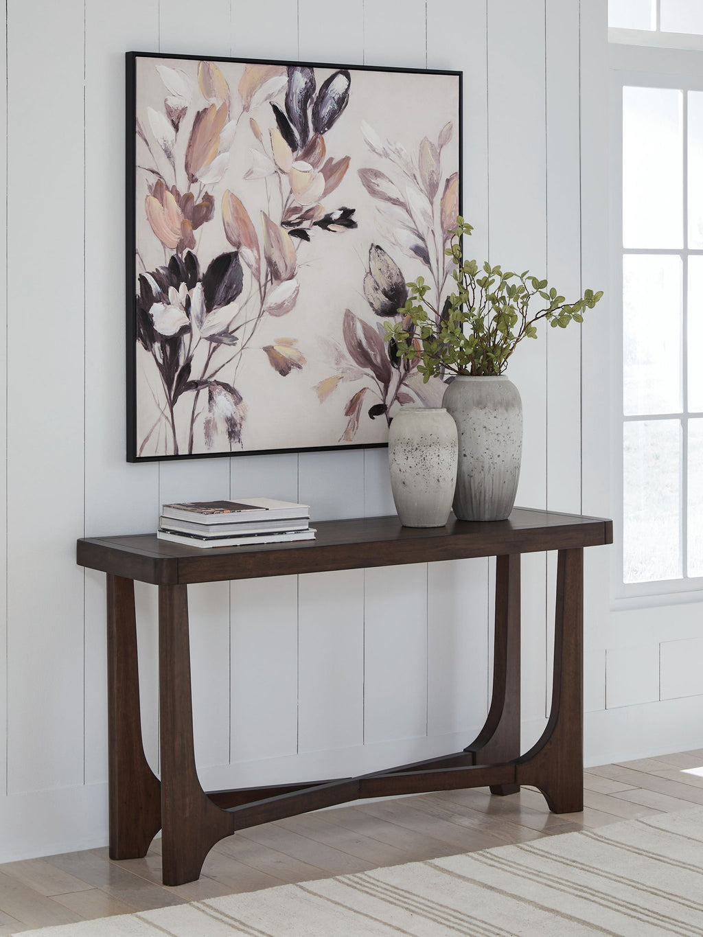 Dark brown rectangular cocktail table with curved apron, styled with books and vase