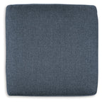 Blue fabric accent ottoman with square profile and rounded top cushion.