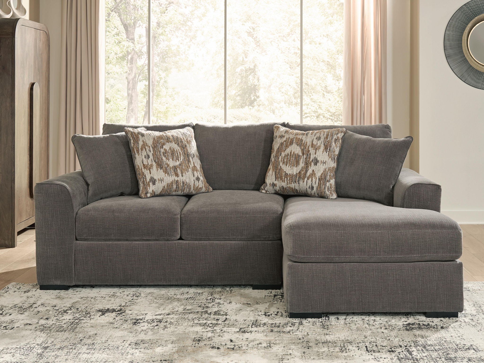 Gray sectional sofa with chaise extension and patterned throw pillows on the backrest