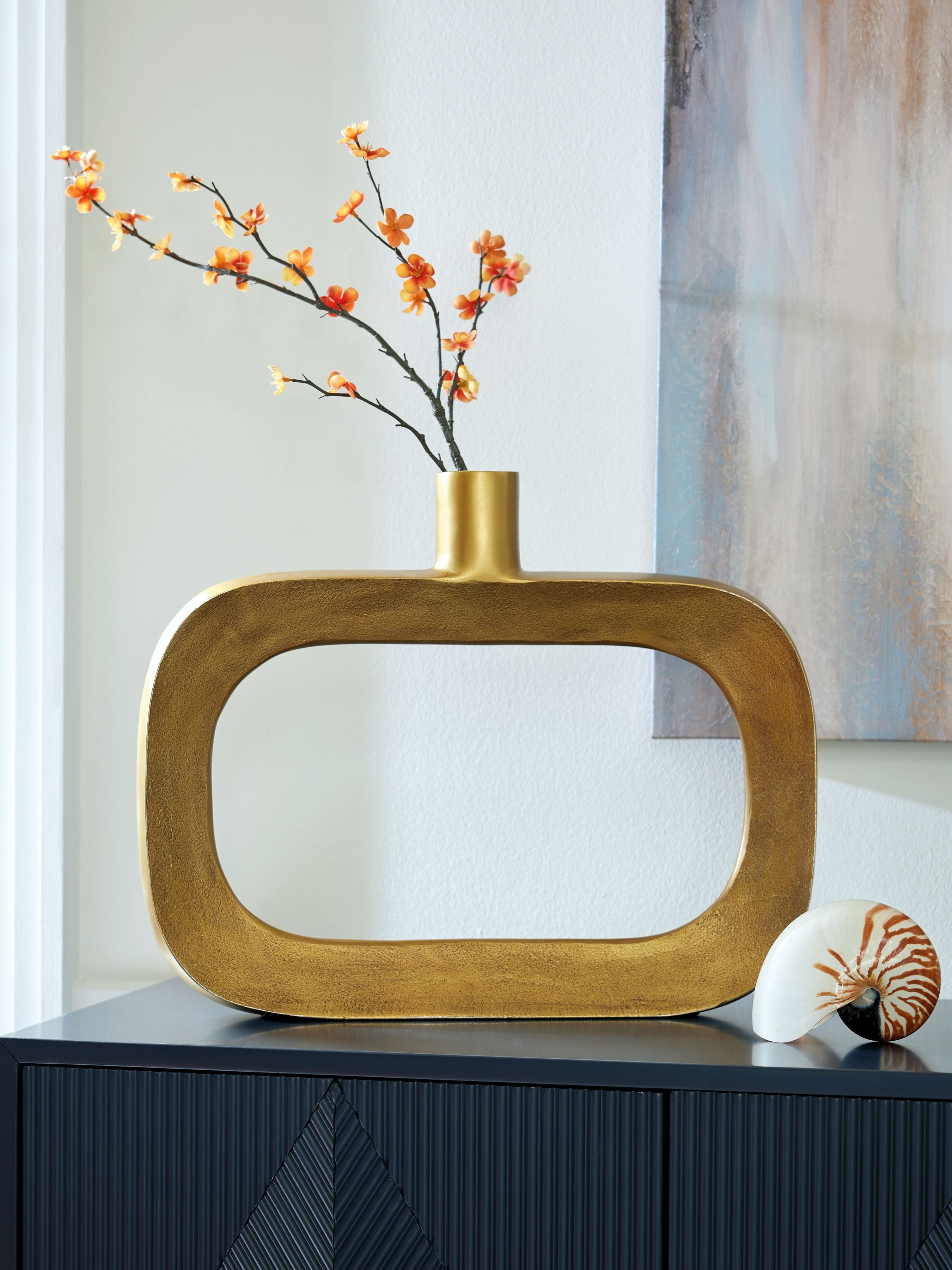 Gold vase holding orange blossoms, with wide oval cutout and neck