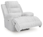 Light gray zero wall recliner with extended footrest, padded armrests, and channel tufting
