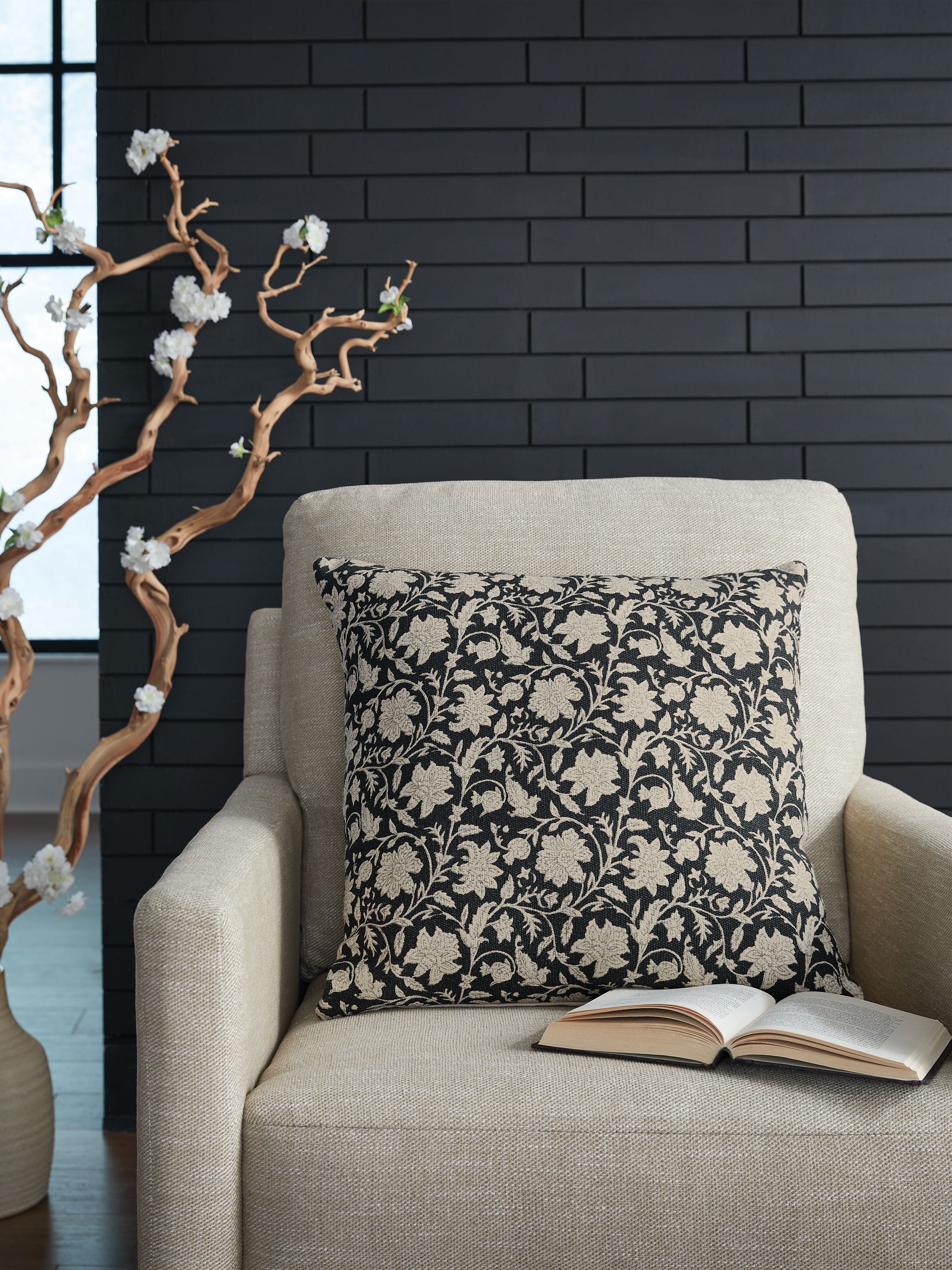 Black and beige floral decorative pillow on a light fabric sofa
