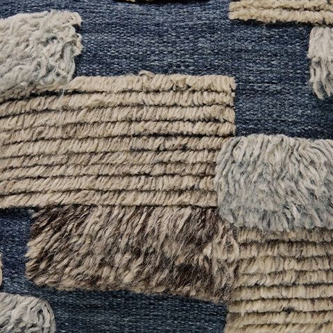 Pillow cover closeup: blue and cream textured patchwork with fringe trim