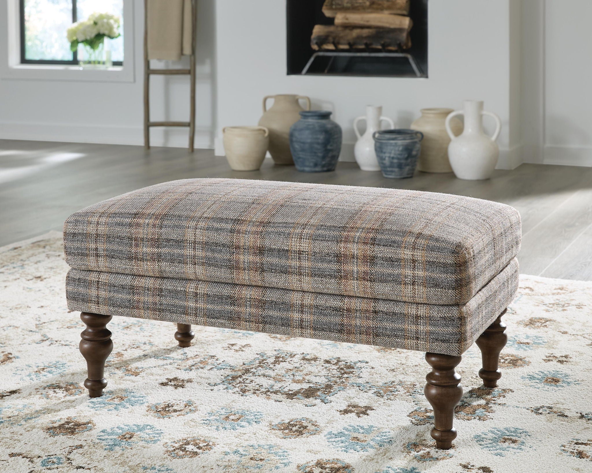 Multi plaid accent ottoman with rounded arms and dark turned wooden legs