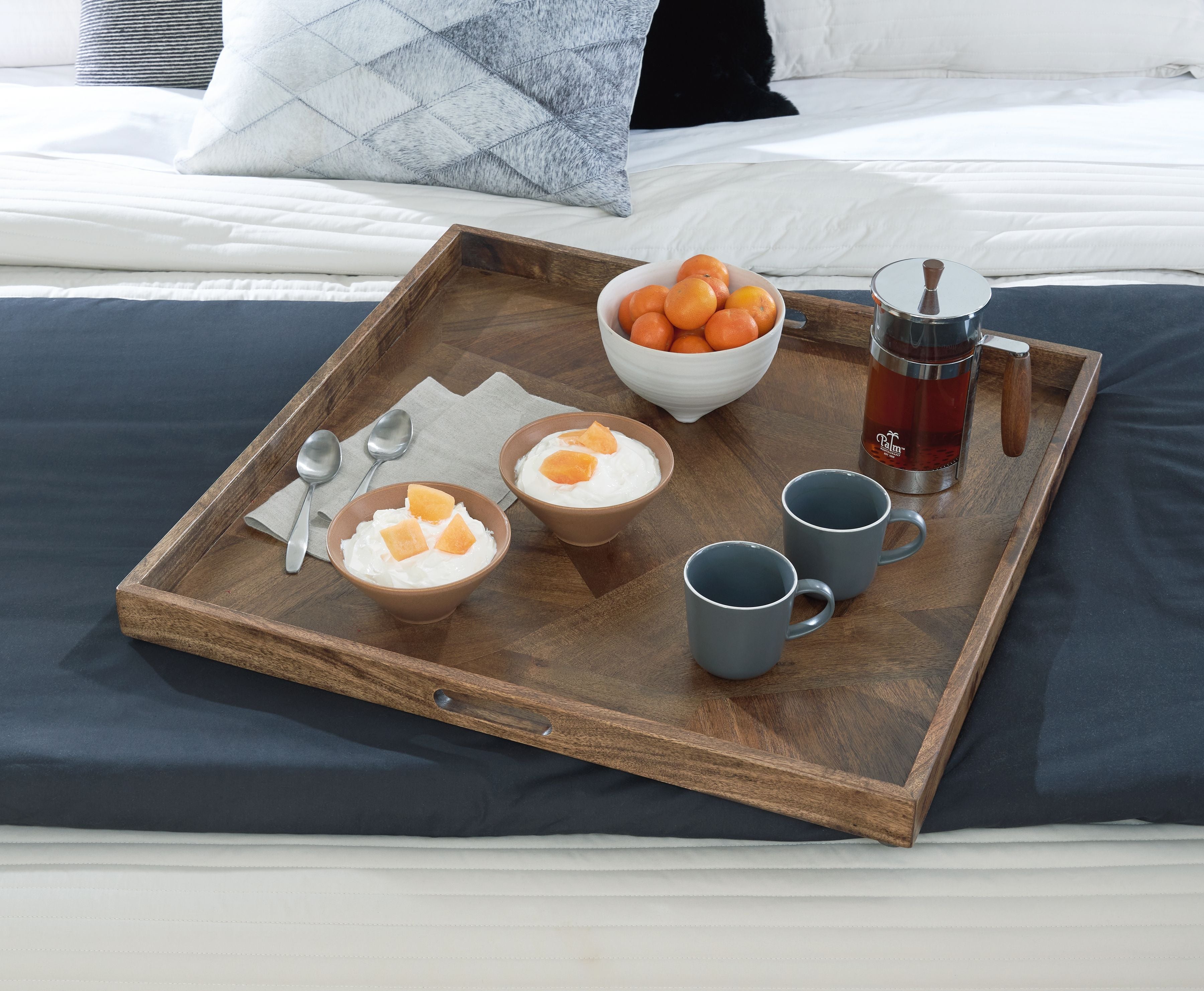 Brown wooden serving tray holding cups, a teapot, and boiled egg halves.