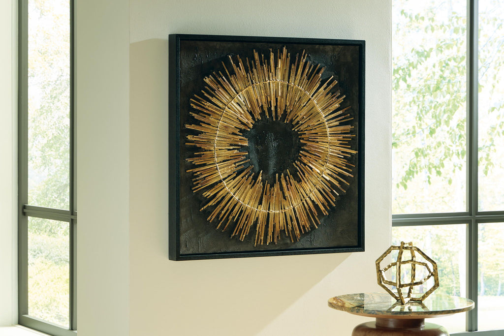 Gold sunburst wall art in a black square frame, mounted on the wall
