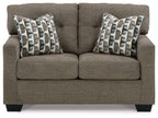 Dark brown loveseat with two patterned throw pillows and thick back cushions