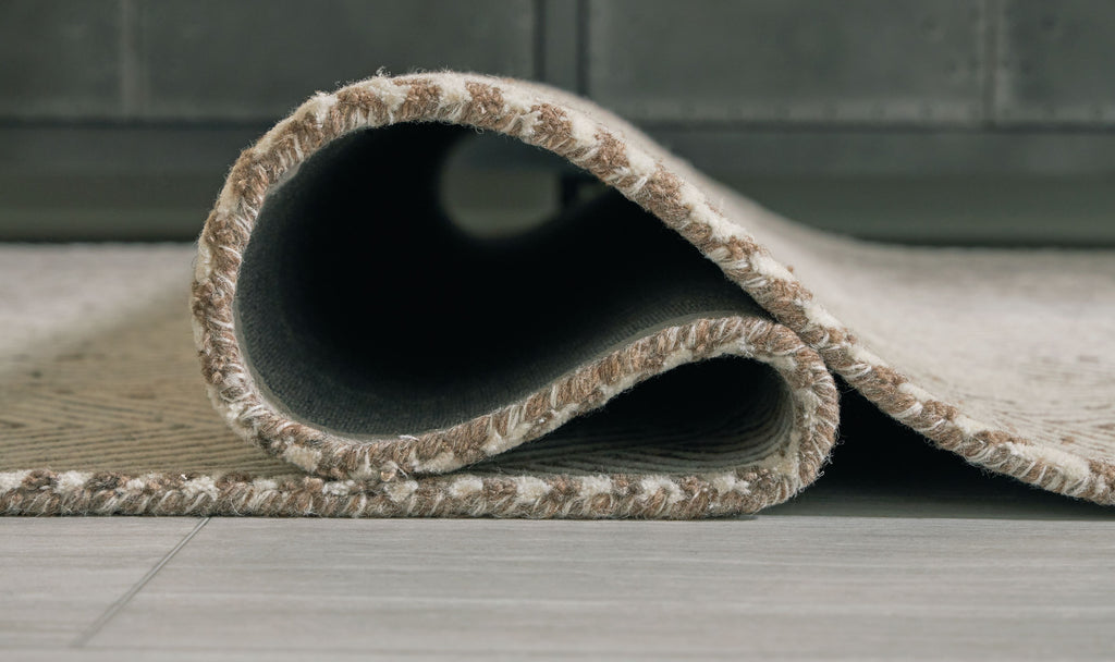 Rolled beige rug showing dark backing and textured weave