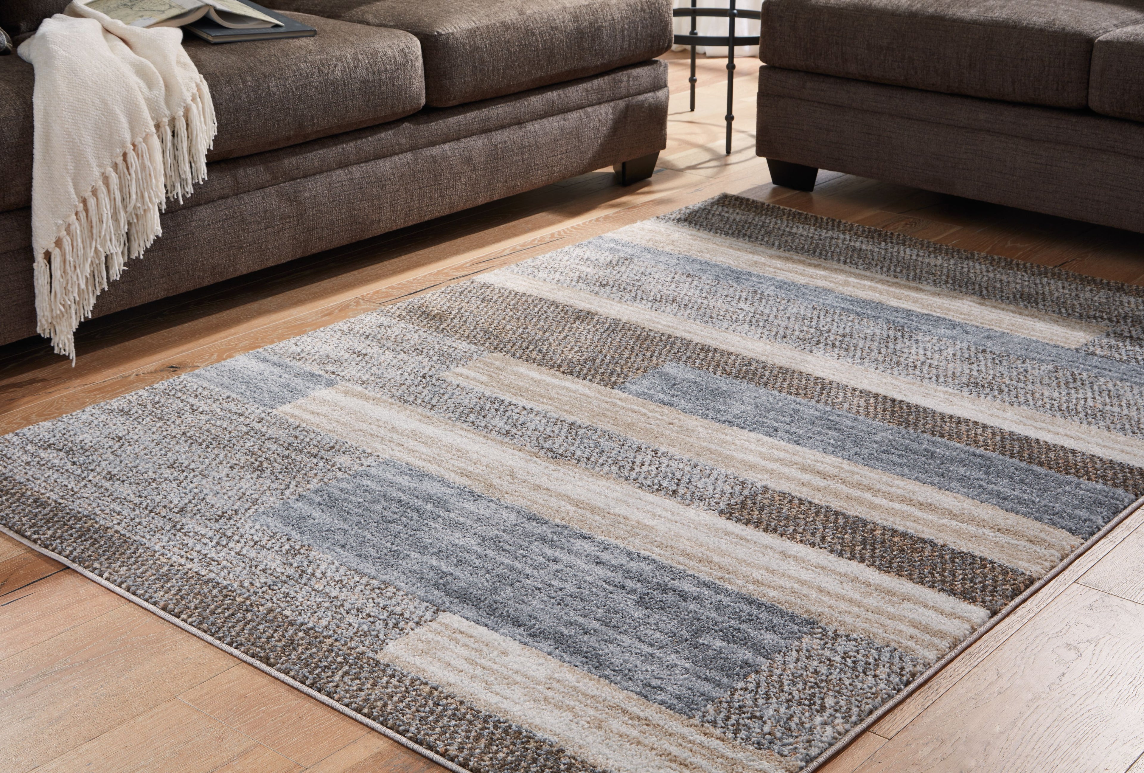 Gray rug with striped blocks and low-cut texture on display