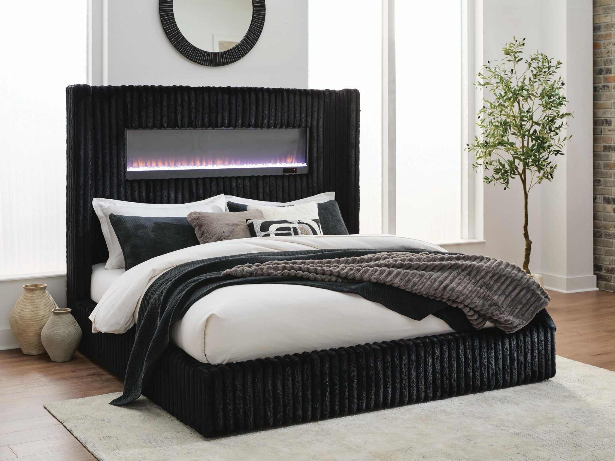 Black upholstered bed with ribbed headboard, fireplace screen, and neatly styled bedding