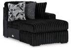 Black ribbed corner chaise with tufted arms and geometric patterned throw pillow